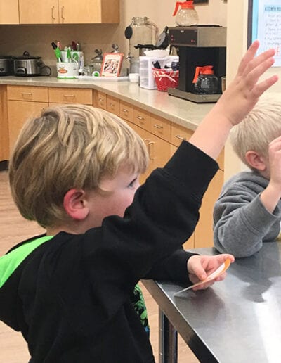 Creative Kids Fort Mill | inquisitive child raising hand in class